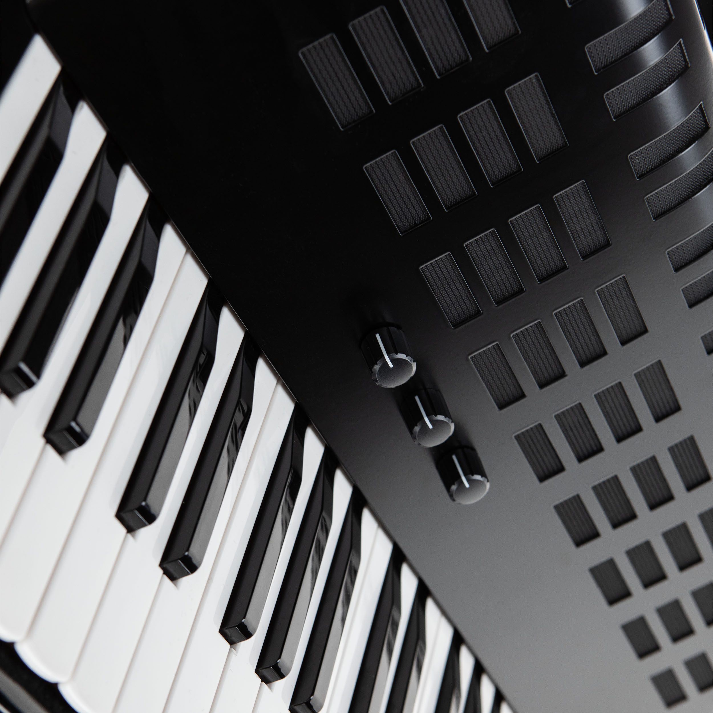 Nahaufnahme einer schwarzen Tastatur mit weißen und schwarzen Tasten sowie drei schwarzen Drehreglern auf der Oberseite